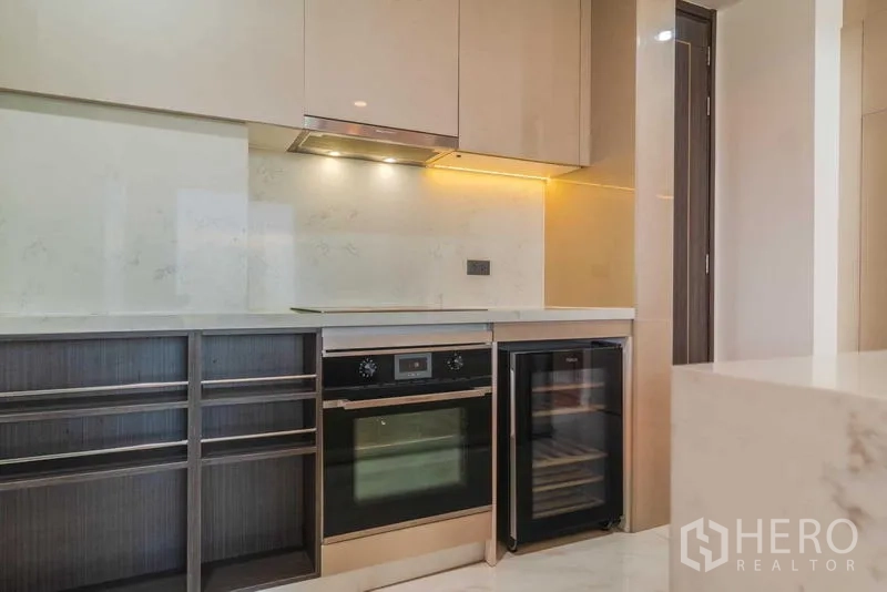 Condominium for rent or sale - Modern kitchen with built-in oven, cooktop, and wine cooler under warm lighting.