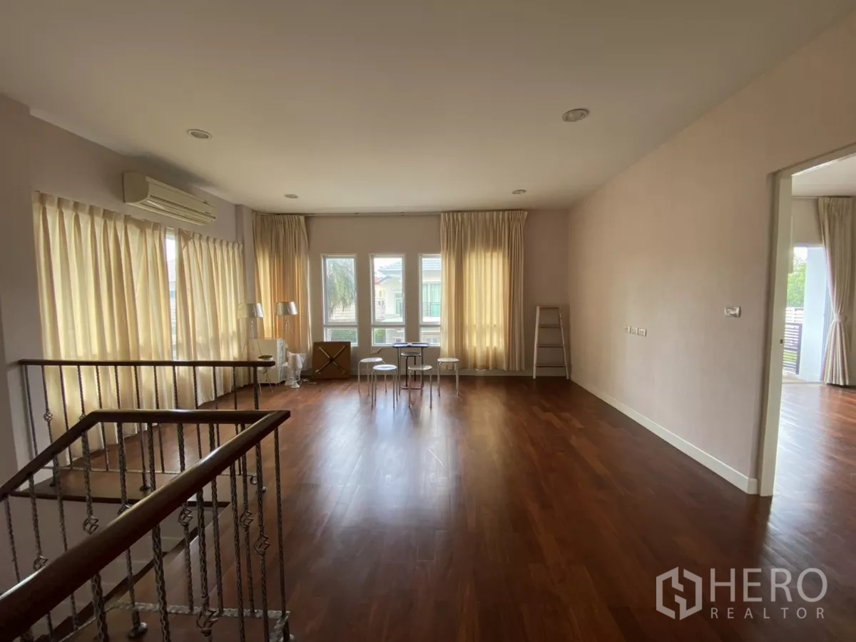 บ้าน ให้เช่าหรือขายในLak Si, Bangkok - ห้องนั่งเล่นแฟมิลี่สว่างไสว มีหน้าต่างบานใหญ่พร้อมผ้าม่านและพื้นไม้.