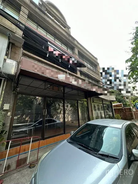 Shophouse for rent in Sathon, Bangkok - Front facade of multi-storey shophouse with wide glass frontage and a parked car.