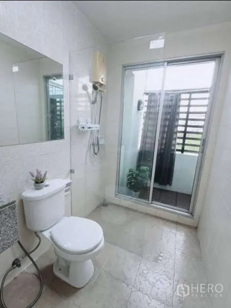 联排别墅 出租在Bang Kapi, Bangkok - 洁净卫生间，淋浴区、坐便器及通向阳台的推拉玻璃门。