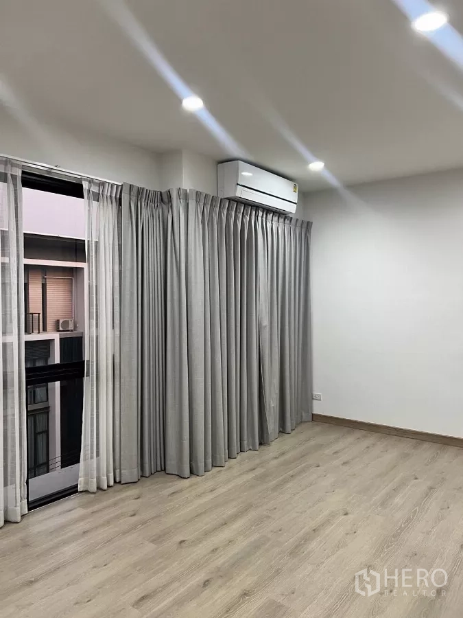 สำนักงานที่บ้าน ให้เช่าในLat Phrao, Bangkok - ห้องมุมพร้อมประตูบานเลื่อน ผ้าม่านสีเทา และแอร์แขวนผนัง