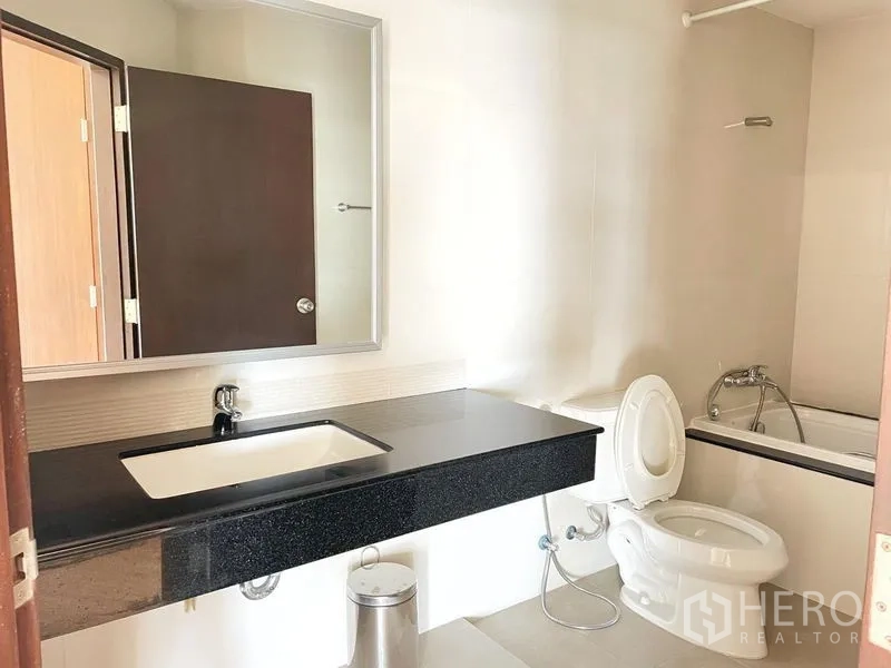 คอนโด ให้เช่าในKhlong Toei, Bangkok - ห้องน้ำพร้อมเคาน์เตอร์อ่างล้างหน้าแกรนิตสีดำ กระจก โถสุขภัณฑ์ และอ่างอาบน้ำฝักบัว
