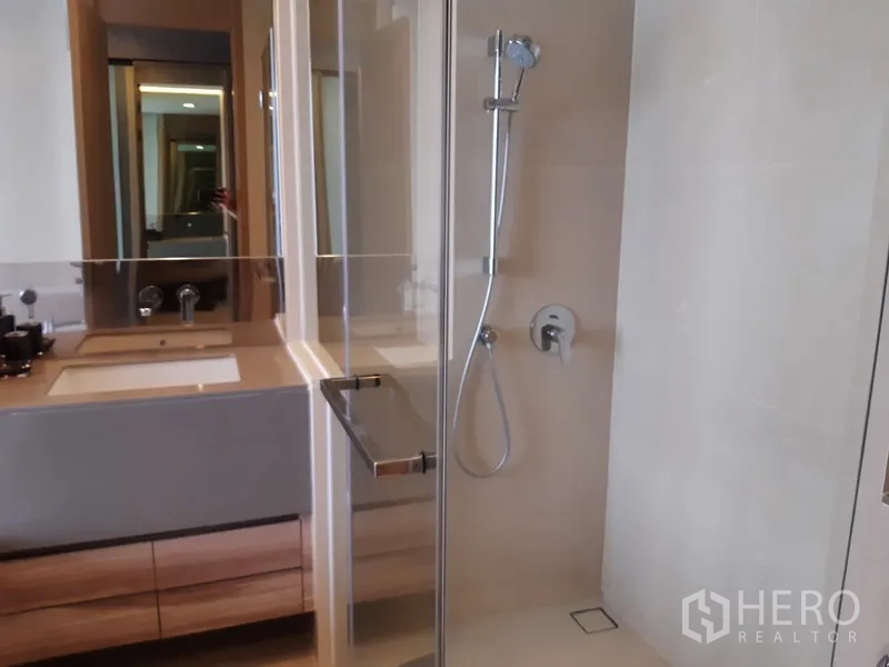 Condominium for rent or sale in Watthana, Bangkok - Contemporary bathroom with glass-enclosed shower and wide vanity.