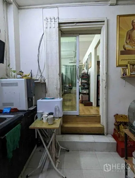 Shophouse for sale in Samphanthawong, Bangkok - Compact pantry with microwave and a sliding glass door leading to a living area in a Bangkok shophouse.