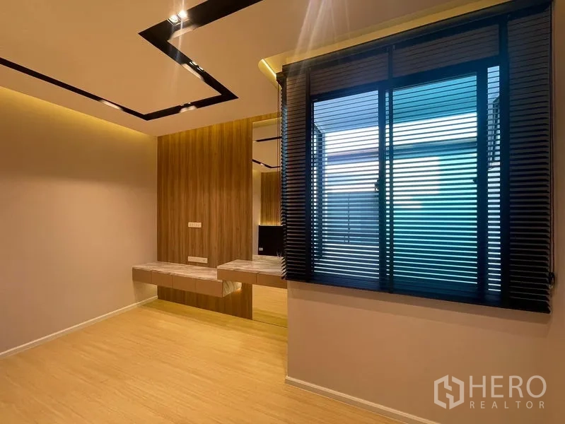 Townhouse for sale - Cozy room with large window, blinds and a floating vanity desk with warm lighting.