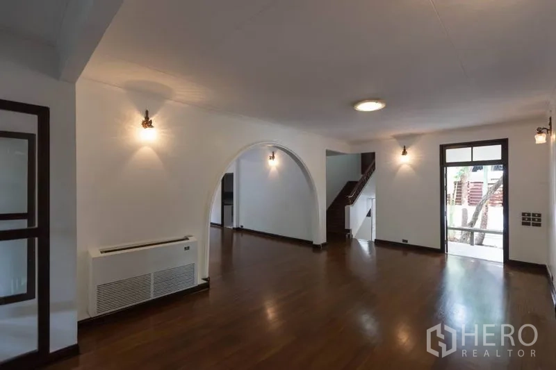 Detached House for rent in Pathum Wan, Bangkok - Living area with arch feature, stairway and door opening to garden terrace.