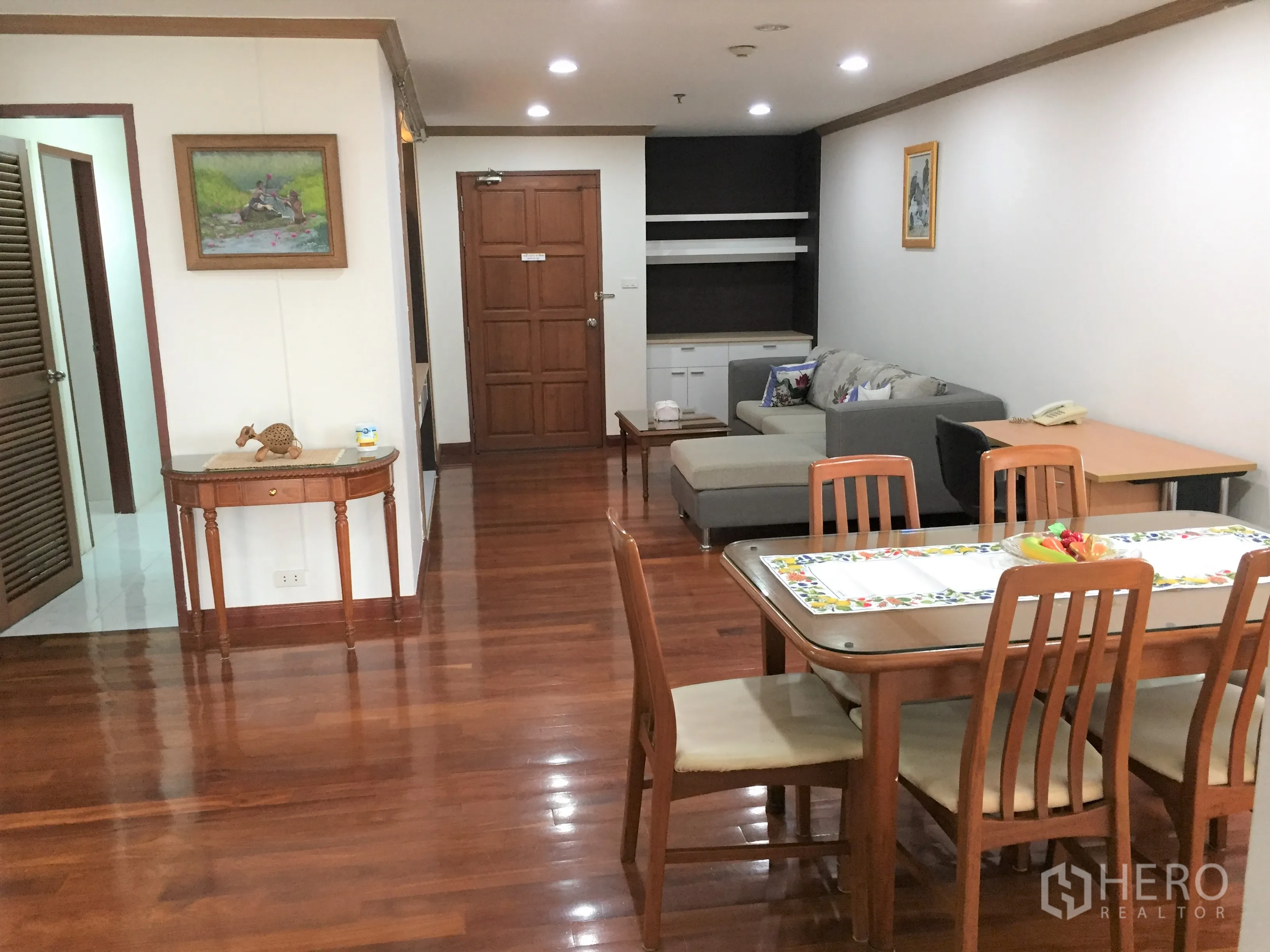 Condominium for rent in Watthana, Bangkok - Spacious living and dining room with recessed lighting, wooden floors and L-shaped sofa.
