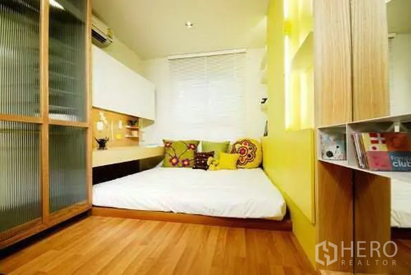 คอนโด ให้เช่าในKhlong San, Bangkok - ห้องนอนอบอุ่น เตียงยกพื้น ผนังสีเหลือง ชั้นวางของ และตู้เสื้อผ้าบานกระจกฝ้า