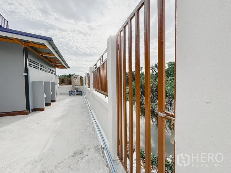 货栈 出租或出售在Khlong Luang, Pathum Thani - 沿水面的围栏，木色竖条栏杆与白色矮墙。