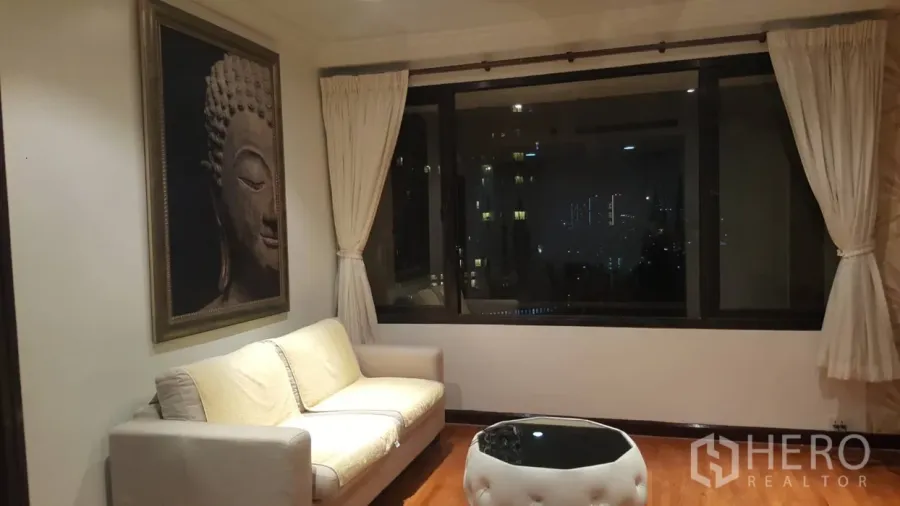 คอนโด ให้เช่าในSathon, Bangkok - มุมนั่งเล่นมีโซฟาสีครีม ภาพศิลปะพุทธรูป และหน้าต่างบานใหญ่ชมแสงไฟเมือง