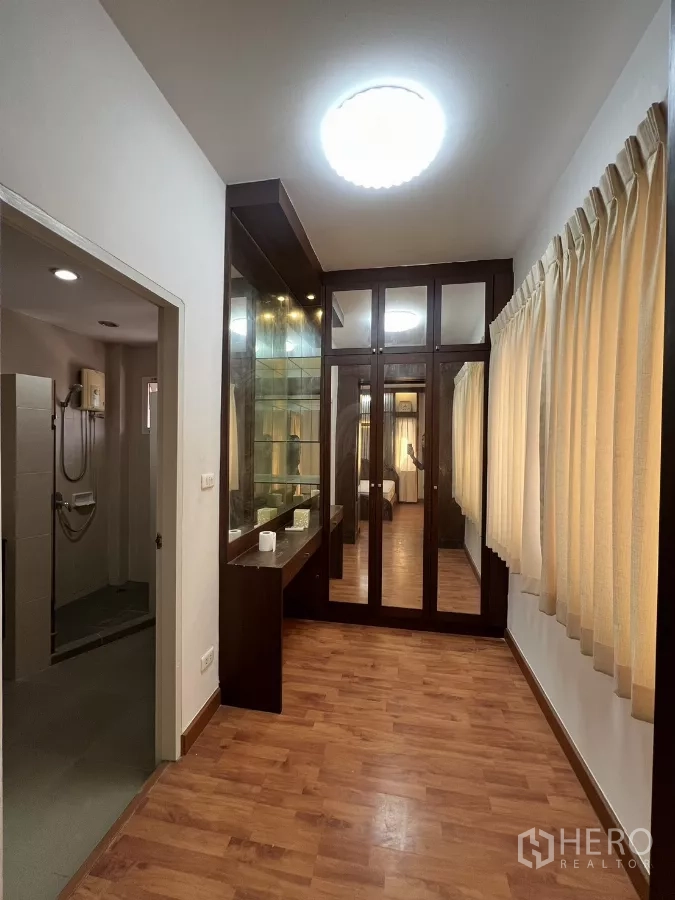 Detached House for rent in Bang Kapi, Bangkok - Walk-in closet corridor with glass display, vanity and access to bathroom.