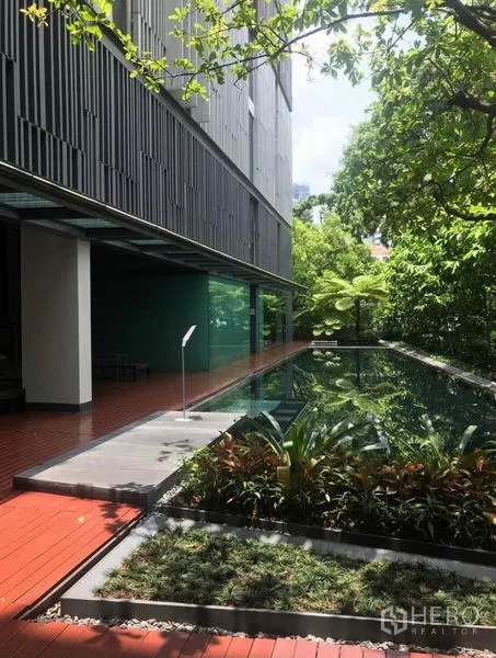 公寓 出租在Watthana, Bangkok - 室外泳池与木质步道，依傍现代公寓立面，被绿意环绕，位于曼谷瓦他那区。