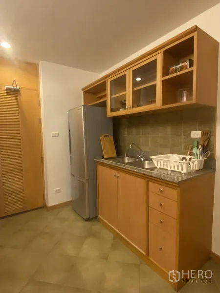 Condominium for rent - Kitchen opposite view showing sink, refrigerator, storage cabinets and tiled backsplash.