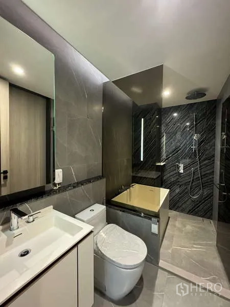 Condominium for rent in Watthana, Bangkok - Modern bathroom with soaking tub, rain shower, and dark stone finishes.
