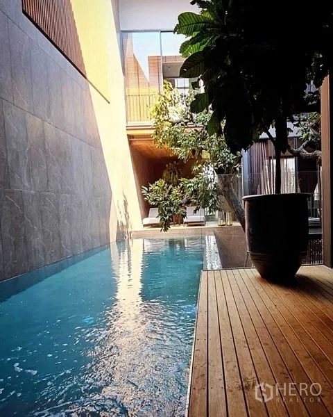 独立式住宅 出售在Lat Phrao, Bangkok - 长条泳池沿木栈道延伸，绿植相伴，午后光影。