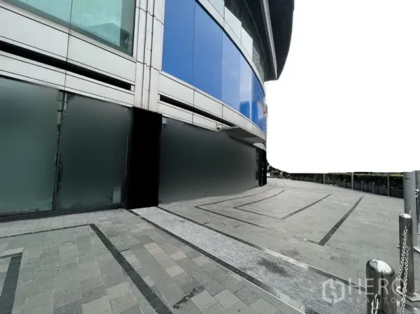 零售空间 出租 - 现代商业建筑的弧形落地玻璃立面，底部磨砂玻璃与宽阔铺装步道