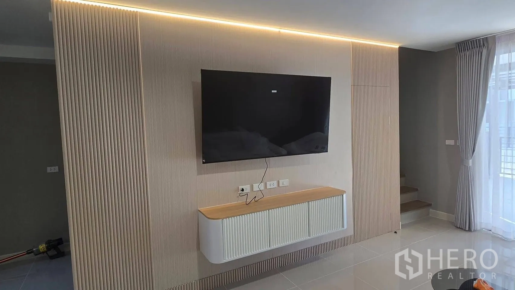 Townhouse for rent in Bang Phli, Samut Prakan - Feature TV wall with wood slats, floating console, and hidden LED lighting.