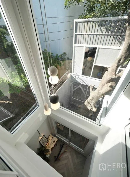 ทาวน์เฮาส์ ให้เช่าในWatthana, Bangkok - โถงบ้านเพดานสูงพร้อมหน้าต่างกระจกเต็มบาน โคมไฟแขวน และวิวคอร์ตยาร์ดมีต้นไม้