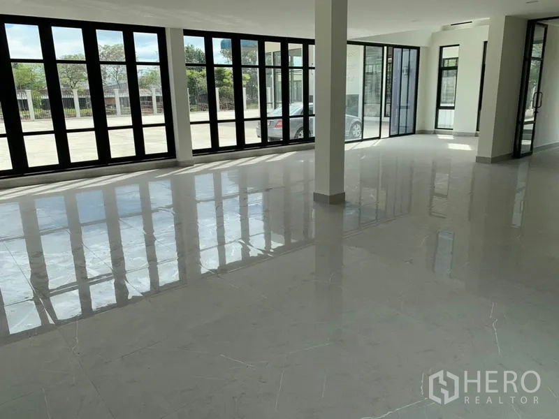 Warehouse for rent in Bang Phli, Samut Prakan - Open-plan showroom or office space with floor-to-ceiling windows and sliding glass doors facing the yard.