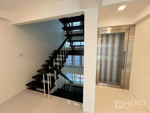 带办公室的家 出租在Khlong Toei, Bangkok - 室内黑色楼梯与不锈钢私家电梯，面向采光中庭。