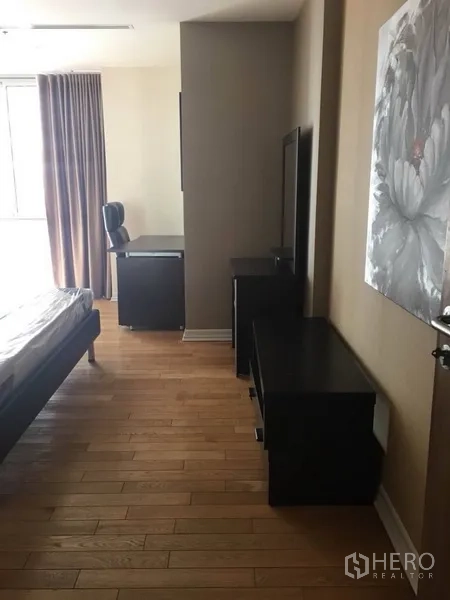 公寓 出租在Bang Rak, Bangkok - 卧室铺木地板，靠窗书桌与深色收纳柜。