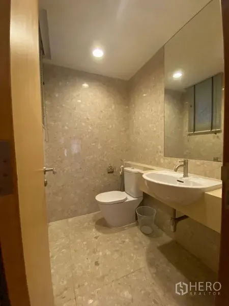 公寓 出租在Watthana, Bangkok - 紧凑客卫，设壁挂台盆、马桶和大镜子，石纹瓷砖铺面。