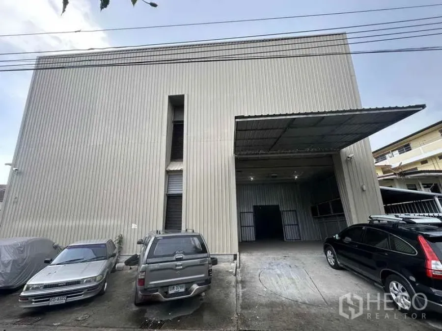 Home Office for rent in Bang Khen, Nonthaburi - Front facade of metal-clad warehouse with a covered loading bay and parking spaces.