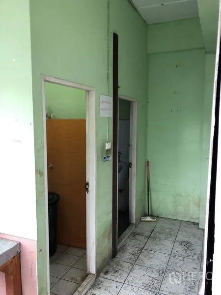 货栈 出租在Nonthaburi - 走廊两侧为卫生间门，淡绿色墙面与瓷砖地面。