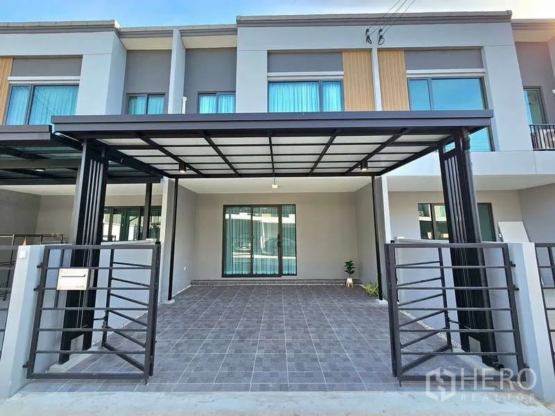 Townhouse for rent in Bang Phli, Samut Prakan - Front view of the townhouse showing tiled driveway and carport roof.