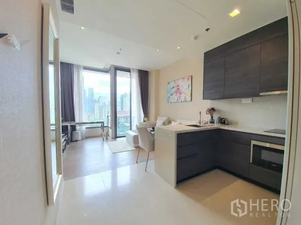 คอนโด ให้เช่าหรือขายในWatthana, Bangkok - ครัวรูปตัวแอลตู้สีเข้ม พร้อมเครื่องใช้บิวท์อิน เชื่อมต่อห้องนั่งเล่นสว่างและระเบียง