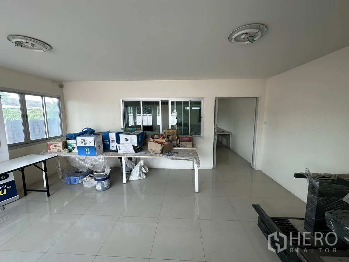Factory for rent in Pathum Thani - Bright office room with tiled floors, wide windows and a sliding service window to a meeting room.