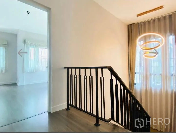 Detached House for sale in Saphan Sung, Bangkok - Upper landing with black metal railing and ring chandelier.