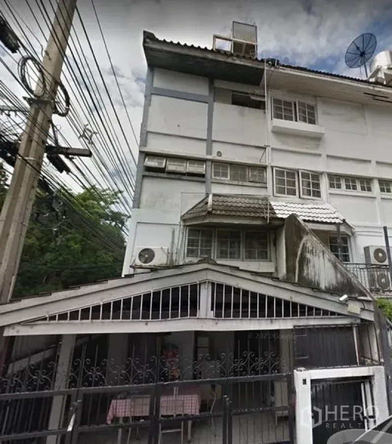 Townhouse for rent in Ratchathewi, Bangkok - Multi-storey townhouse exterior in Asoke, Huai Khwang with a gated carport, metal fence, wall-mounted AC units, satellite dish and overhead power lines.