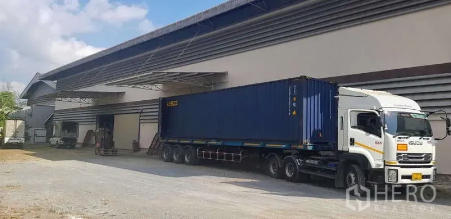 Warehouse for rent in Sam Phran, Nakhon Pathom - Warehouse frontage with wide driveway and covered loading zone for trailer access.