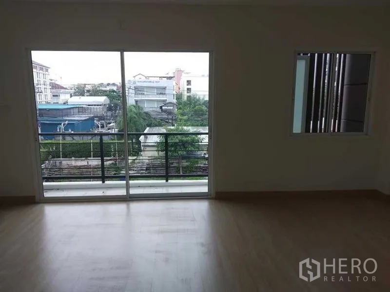 带办公室的家 出租在Prawet, Bangkok - 采光充足的房间，推拉玻璃门通向阳台，俯瞰社区景观。