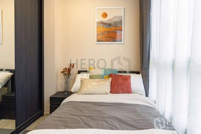Condominium for rent or sale - Sunlit bedroom with floor-to-ceiling window and neutral decor.