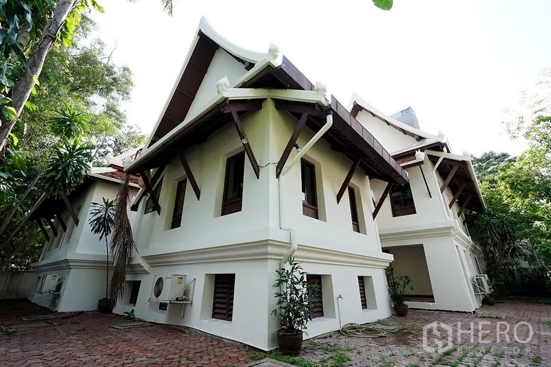 บ้าน ให้เช่าในWatthana, Bangkok - ด้านข้างตัวบ้านโชว์ชายคาเด่น ลานปูอิฐ เครื่องปรับอากาศ และต้นไม้เขตร้อน