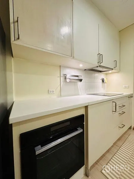 公寓 出租在Bang Rak, Bangkok - 一字型现代厨房，白色橱柜、嵌入式烤箱与电磁炉。