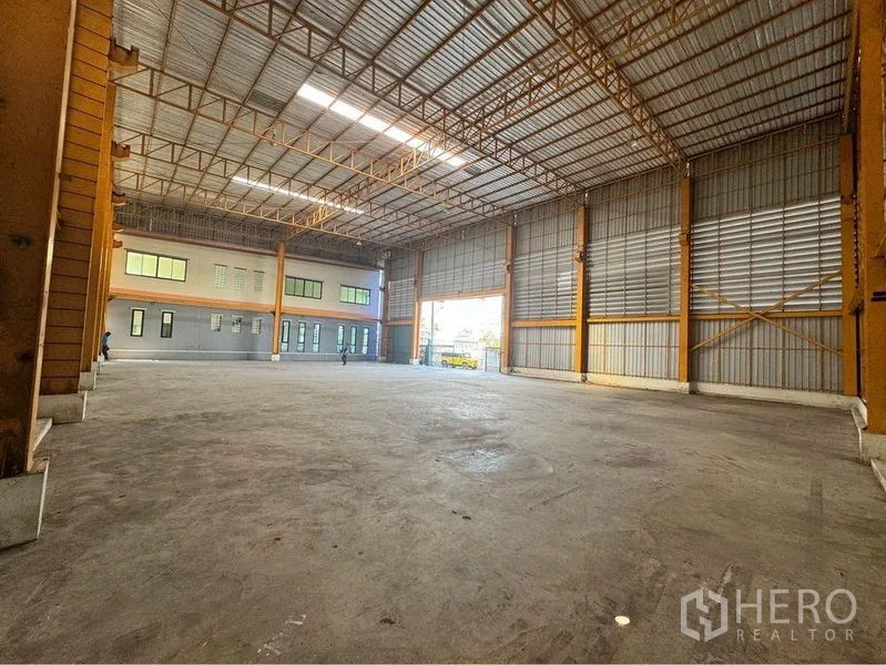 Warehouse for rent or sale in Mueang Samut Sakhon, Samut Sakhon - Wide-span warehouse interior with high roof, loading gate, and smooth concrete floor for trucks.