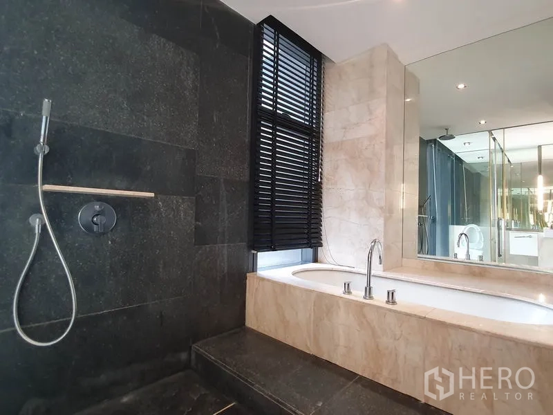 公寓 出租在Sathon, Bangkok - 卫浴设浴缸与独立淋浴，深色石墙与大镜子。