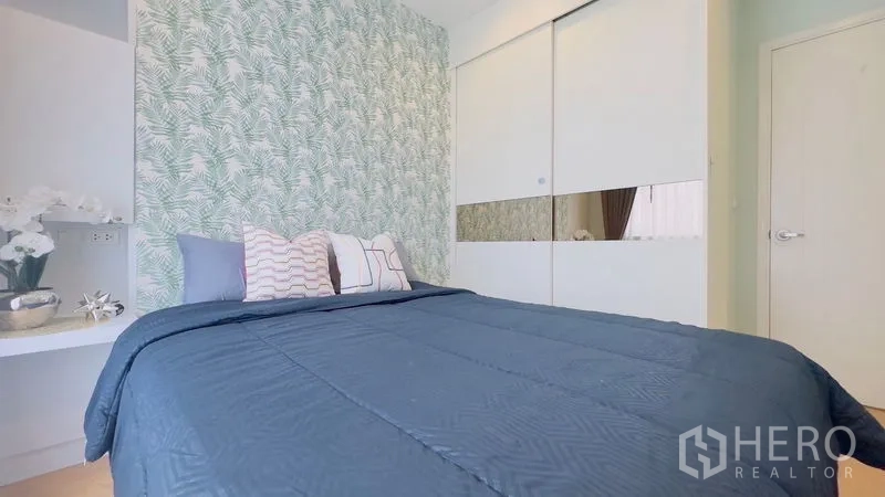 คอนโด ให้เช่าในWatthana, Bangkok - ห้องนอนอบอุ่น ผนังลายใบไม้ ชุดเครื่องนอนสีน้ำเงิน และตู้เสื้อผ้าบานเลื่อน