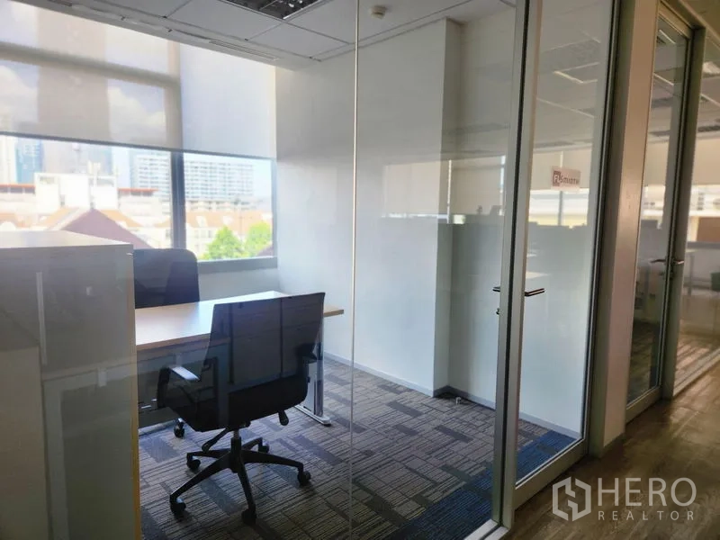 Office Space for rent - Private office behind glass walls with a single desk, task chair and skyline view.