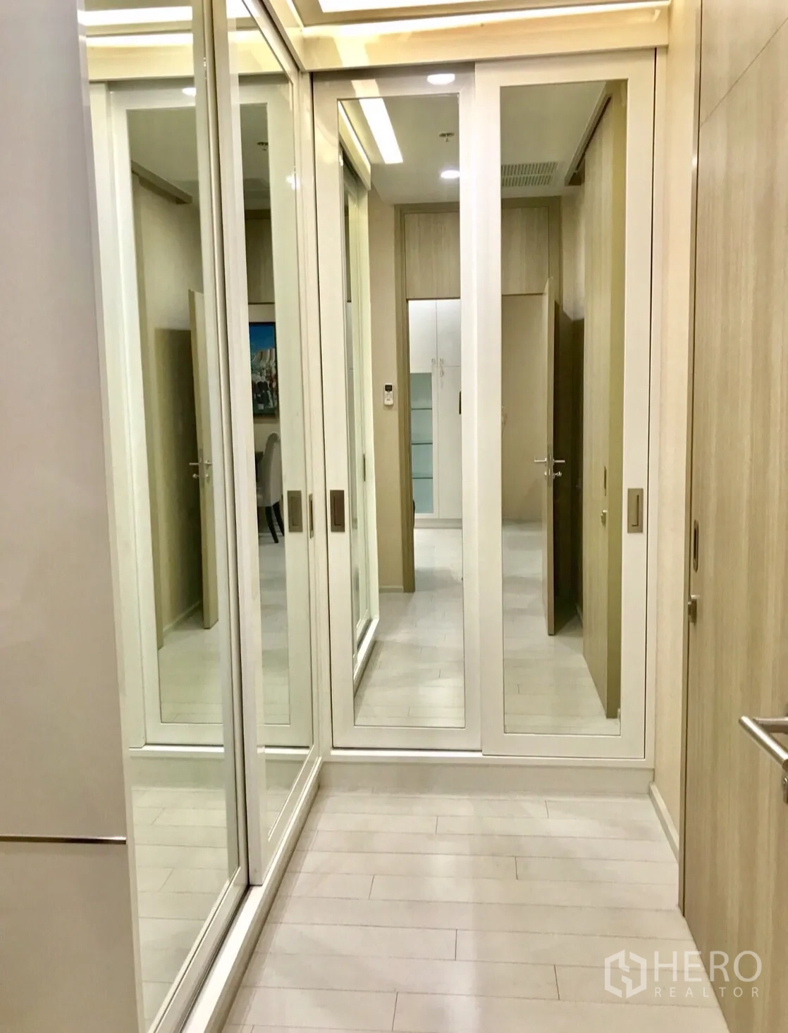 Condominium for rent in Pathum Wan, Bangkok - Walk-in closet corridor featuring full-height mirrored wardrobes and light wood floors.