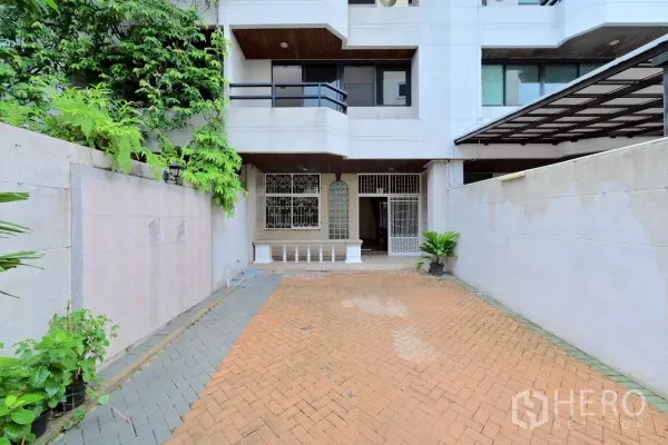 Townhouse for sale in Watthana, Bangkok - Multi-storey townhouse exterior with gated driveway and small front patio.