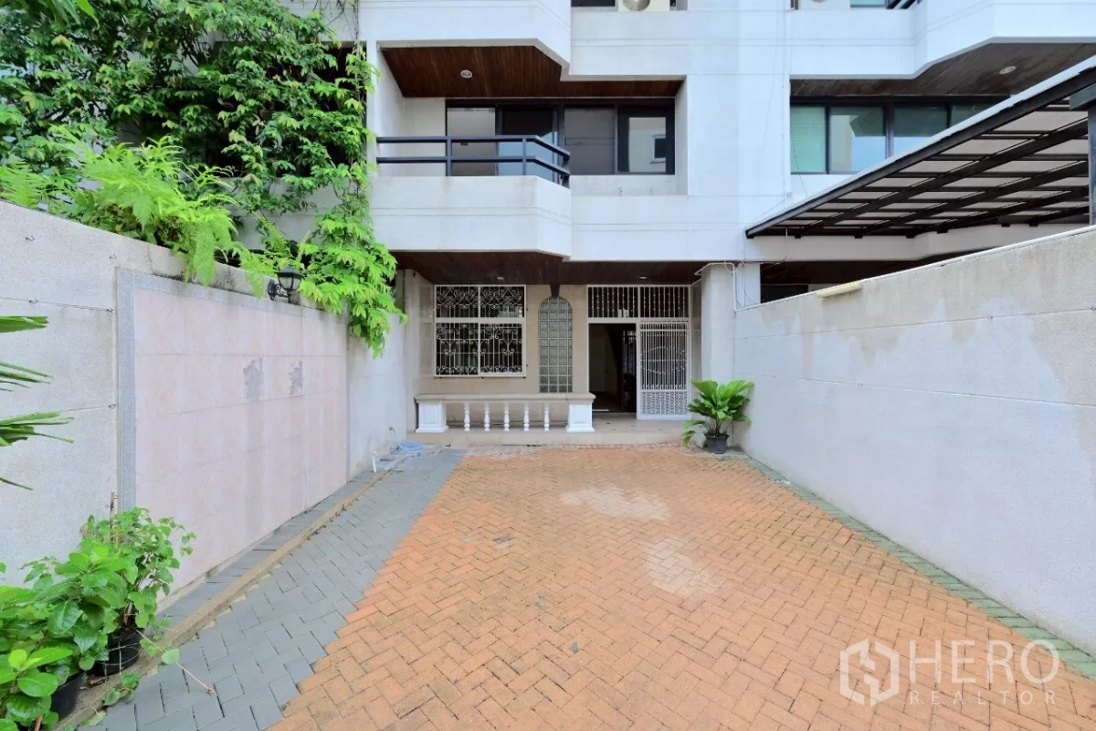 Townhouse for sale in Watthana, Bangkok - Multi-storey townhouse exterior with gated driveway and small front patio.