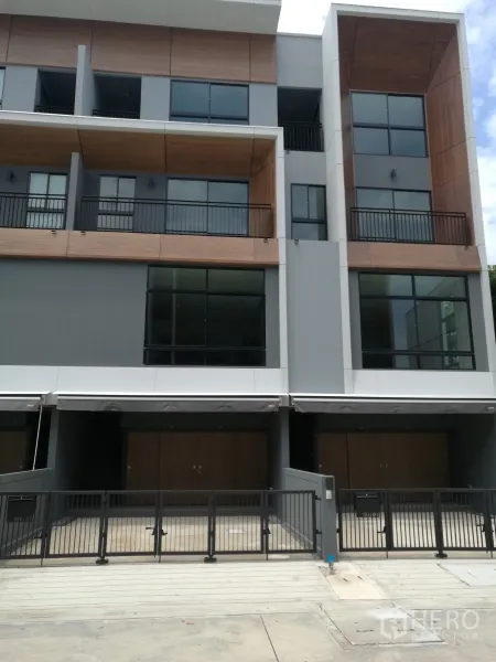 Townhouse for rent in Suan Luang, Bangkok - Modern three-storey townhouse facade with balconies and gated parking.