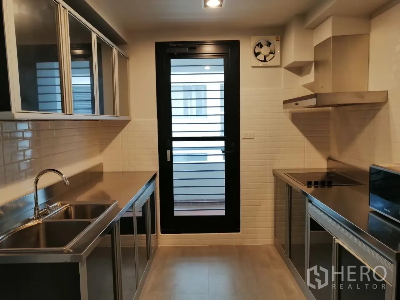 อพาร์ทเมนท์ ให้เช่าในKhlong Toei, Bangkok - ครัวแบบแกลเลอรี่ อ่างล้างจานคู่ ตู้แขวน และประตูออกสู่ระเบียงหรือโซนซักล้าง