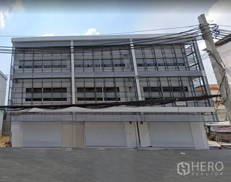 Shophouse for rent in Lat Phrao, Bangkok - Modern multi-storey shophouse facade with several roller shutters and grid-style windows on a quiet Lat Phrao street.