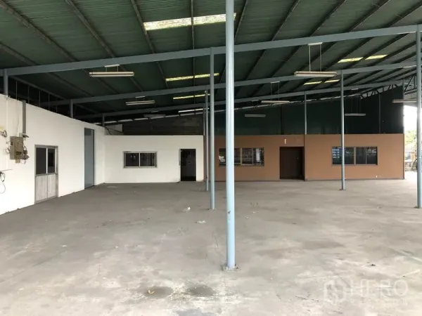 Warehouse for rent in Bang Phli, Samut Prakan - Wide warehouse bay with steel columns, bright lighting, and attached office section along the wall.