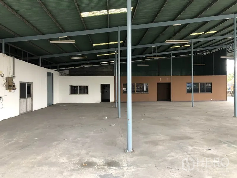 Warehouse for rent in Bang Phli, Samut Prakan - Wide warehouse bay with steel columns, bright lighting, and attached office section along the wall.